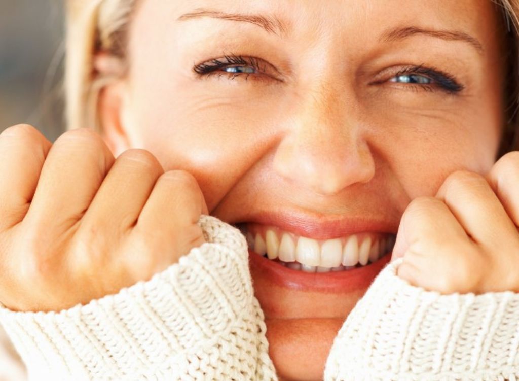 A close up of a smiling woman with bright healthy skin.