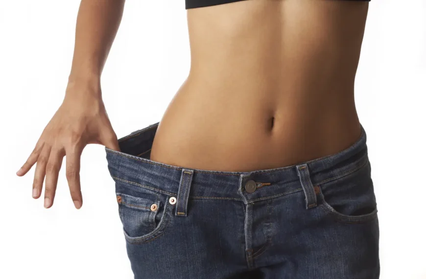 Close-up of woman's midsection in jeans, pulling fabric away to reveal slimmer contours and reduced body fat.